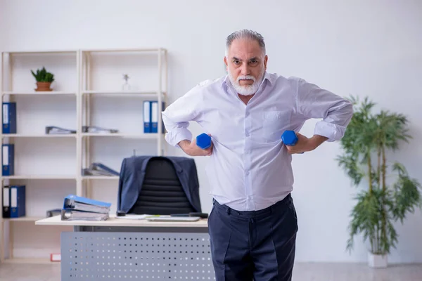 Verouderde mannelijke werknemer doet fysieke oefeningen tijdens de pauze — Stockfoto