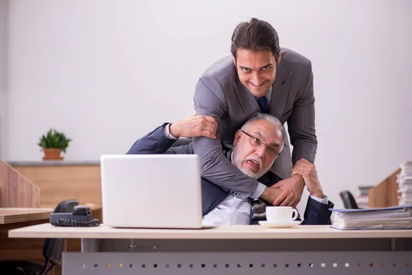 Velho chefe e jovem assistente masculino no escritório — Fotografia de Stock