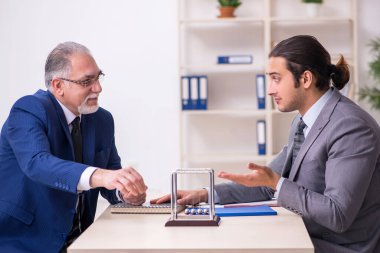 Masada iki iş adamı ve meditasyon topu var.