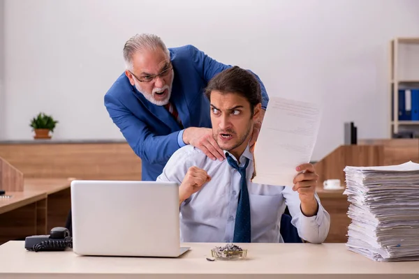 Jeune employé et vieux patron brûlant des papiers sur le lieu de travail — Photo