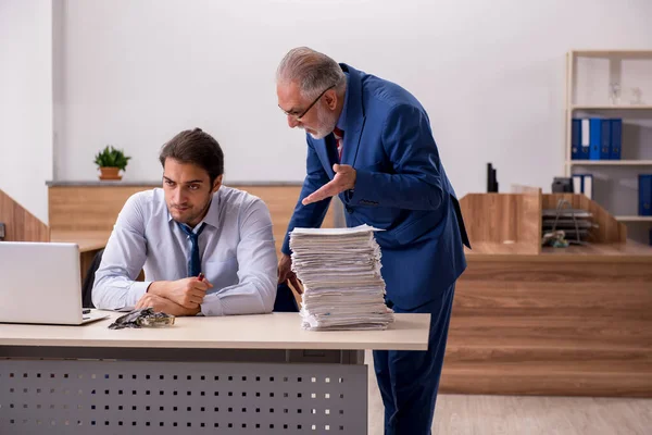 Genç erkek çalışan ve yaşlı patron iş yerinde kağıtları yakıyor.