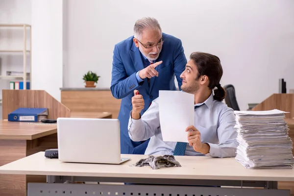 Joven empleado masculino y viejo jefe quemando papeles en el lugar de trabajo — Foto de Stock