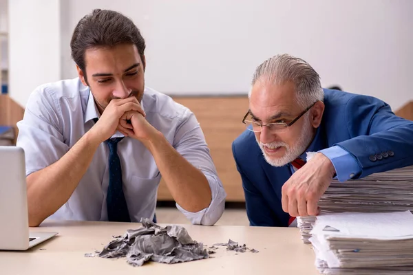 Giovane dipendente maschio e vecchio capo bruciando documenti sul posto di lavoro — Foto Stock