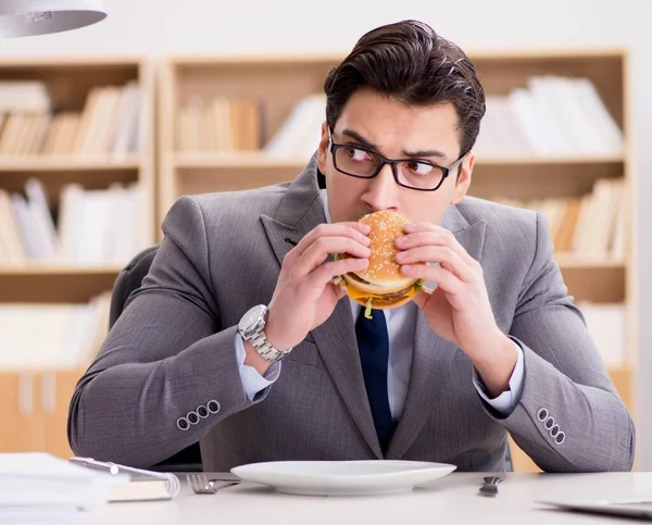 Hambriento empresario divertido comer sándwich de comida chatarra — Foto de Stock
