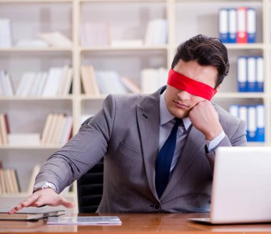 Ofiste masasında oturan gözü bağlı iş adamı.