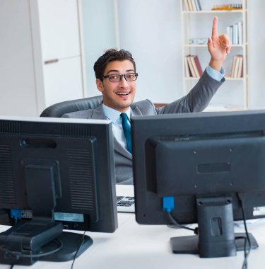 Birçok ekranın önünde oturan bir iş adamı