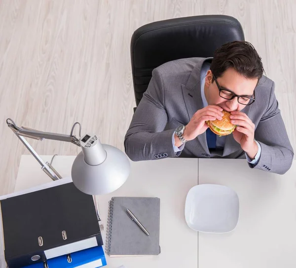 Hambriento empresario divertido comer sándwich de comida chatarra — Foto de Stock