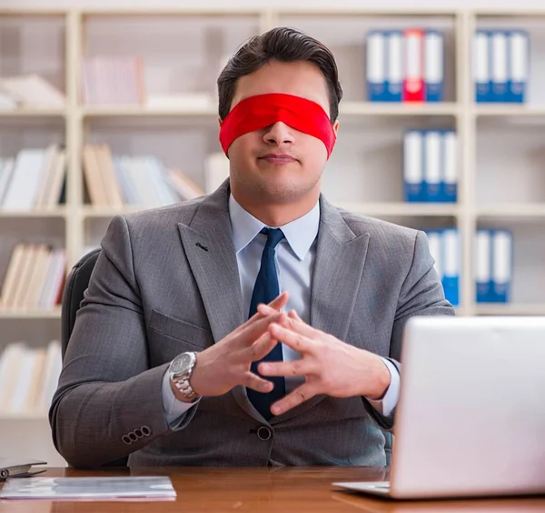 Ofiste masasında oturan gözü bağlı iş adamı.