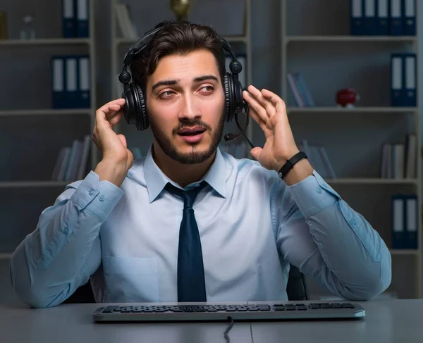 Ung man i call center koncept som arbetar sent övertid på kontoret — Stockfoto