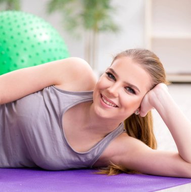 Spor salonunda denge topuyla egzersiz yapan genç bir kadın.