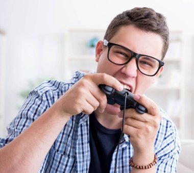 Genç adam evde bilgisayar oyunu oynuyor.