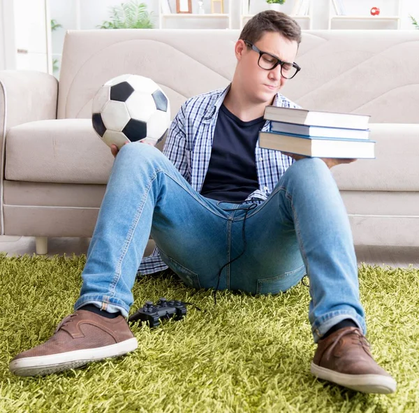 Jovem estudante tentando equilibrar estudar e jogar futebol — Fotografia de Stock