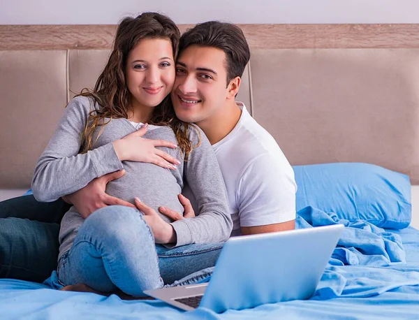 Ung familj med gravid fru väntar barn i sängen — Stockfoto