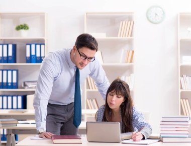 Erkek öğretim görevlisi bayan öğrenciye ders veriyor.