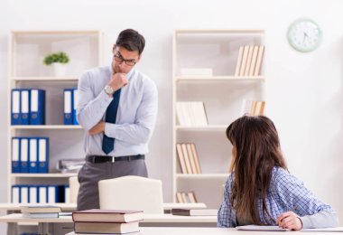 Erkek öğretim görevlisi bayan öğrenciye ders veriyor.