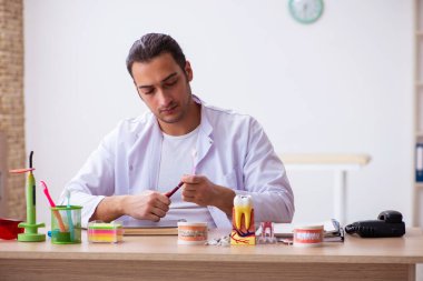 Klinikte çalışan genç erkek dişçi.
