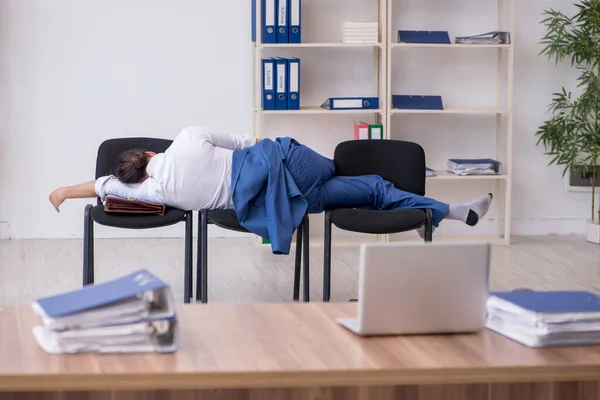 Jeune employé masculin dormant dans le bureau sur des chaises — Photo