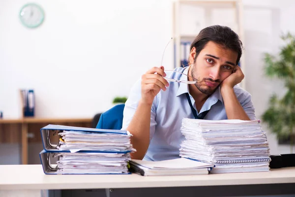 Jonge mannelijke werknemer ongelukkig met overmatig werk in het kantoor Rechtenvrije Stockfoto's