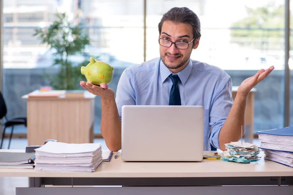 Jovem contabilista masculino segurando porquinho banco no local de trabalho — Fotografia de Stock