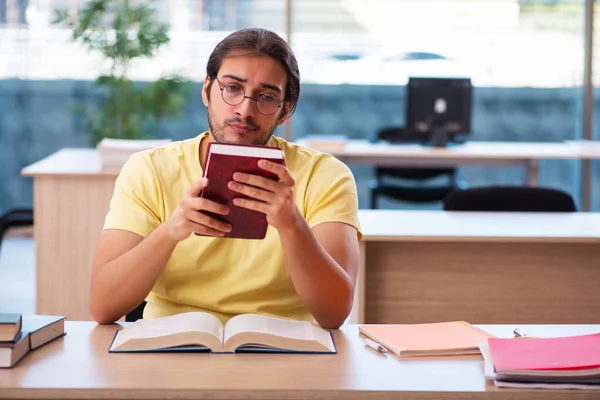 Jonge mannelijke student bereidt zich voor op examens in de klas — Stockfoto