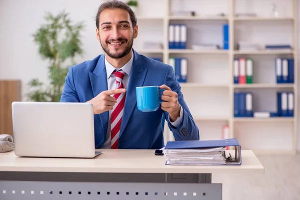 Jonge mannelijke werknemer die koffie drinkt op het werk — Stockfoto