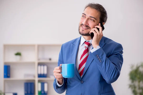 Jovem funcionário do sexo masculino bebendo café no local de trabalho — Fotografia de Stock