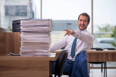 Ofisteki aşırı işten memnun olmayan genç bir erkek işçi.