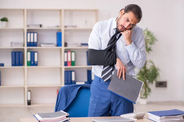 Young arm injured male employee working in the office — Stock Photo, Image