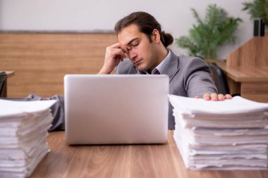 Ofisteki aşırı işten memnun olmayan genç bir erkek işçi.