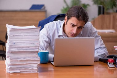 Ofisteki aşırı işten memnun olmayan genç bir erkek işçi.