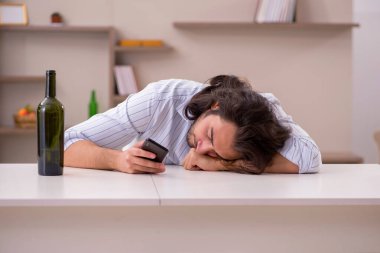 Genç adam evde alkol içiyor.