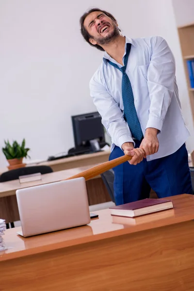 Jovem homem furioso empregado segurando bastão de beisebol no escritório — Fotografia de Stock