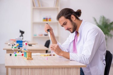 Sınıftaki masada oturan genç bir kimyager.