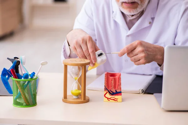 Homem velho dentista que trabalha na clínica — Fotografia de Stock