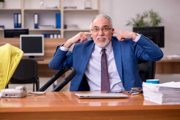 Aged businessman employee looking after newborn at workplace