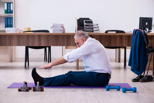 Old businessman employee doing sport exercises in the office — Stock Photo, Image