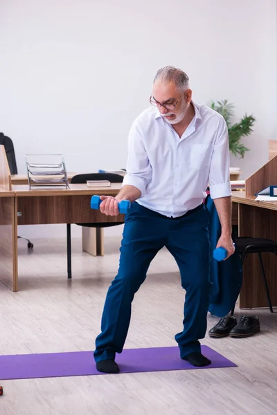 Old businessman employee doing sport exercises in the office — Stock Photo, Image