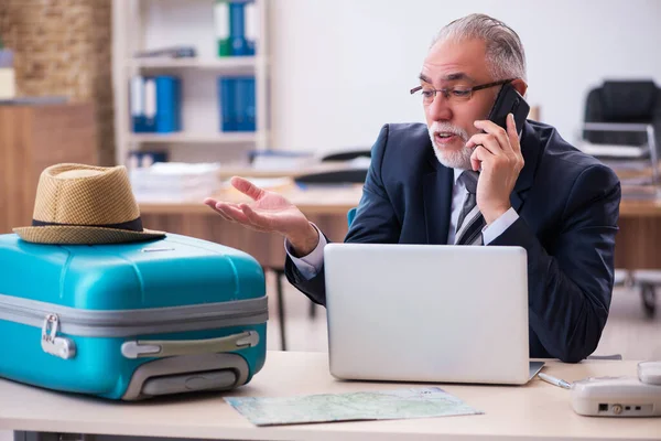 Old male employee preparing for travel in the office — Stock Photo, Image