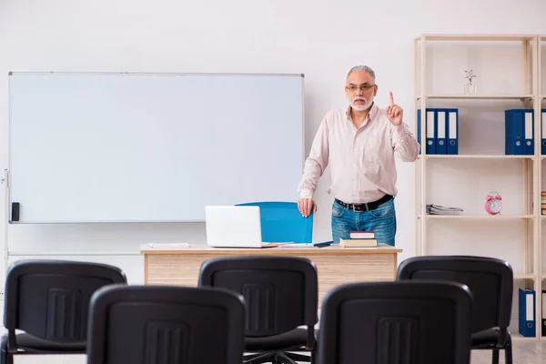 Velho professor do sexo masculino em sala de aula em conceito pandêmico — Fotografia de Stock
