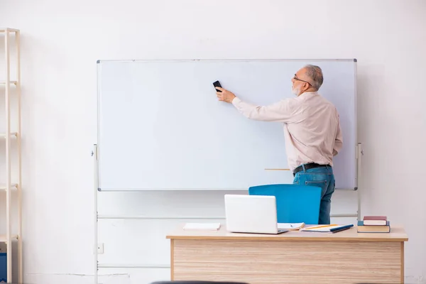 Oude mannelijke leraar in het klaslokaal in pandemisch concept — Stockfoto