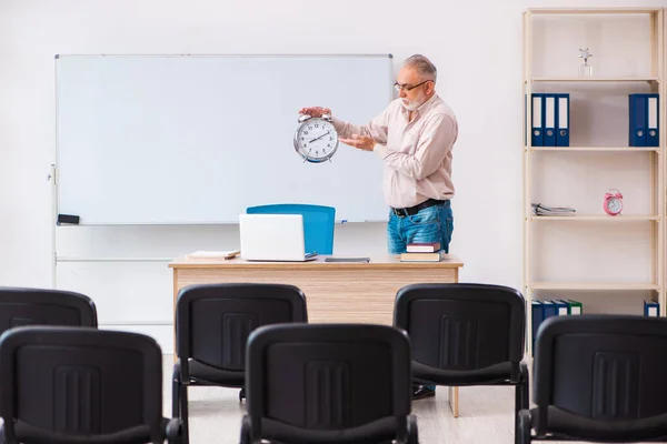 Oude mannelijke leraar in het klaslokaal in time management concept — Stockfoto
