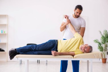 Yaşlı erkek hasta, genç erkek doktor masörünü ziyaret ediyor.