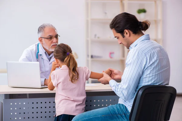 Piccola ragazza con suo padre in visita vecchio medico maschio — Foto Stock