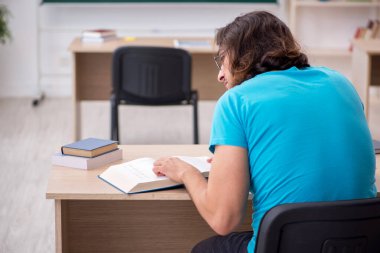 Yeşil panonun önünde genç bir erkek öğrenci.