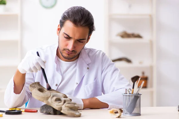 Jonge mannelijke archeoloog bestudeert het oude Afrikaanse steenmasker — Stockfoto