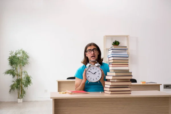 Young male student and a lot of books in the class