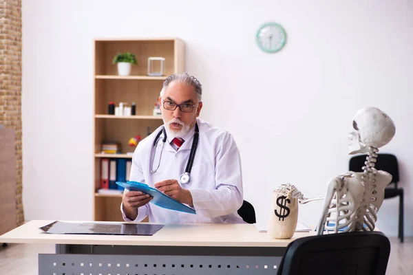 Old male doctor cardiologist and skeleton patient in expensive m — Stock Photo, Image