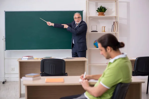 Aged teacher and young male student in the classroom — Stock Photo, Image