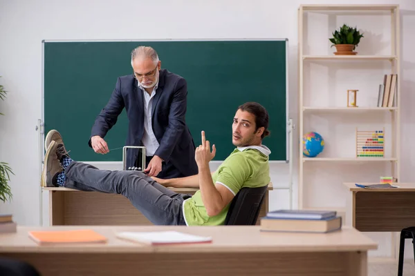 Aged physics teacher and male student in the classroom