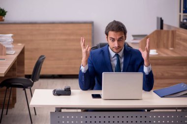 Genç adam işyerinde oturuyor.